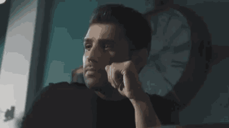 a man sitting in front of a clock looking at something