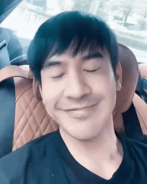 a man sitting in a car with his eyes closed and a smile on his face