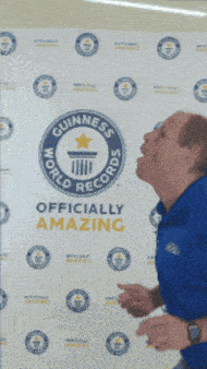 a man in a blue shirt is standing in front of a world record sign
