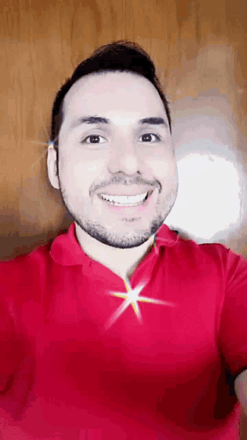 a man with a beard is wearing a red shirt and smiling for the camera