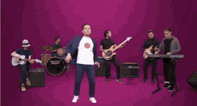 a man in a white shirt is dancing in front of a m-audio keyboard