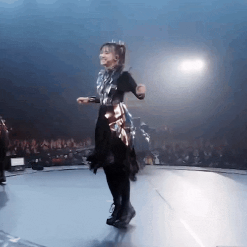 a woman in a dress is dancing on a stage in front of a crowd .