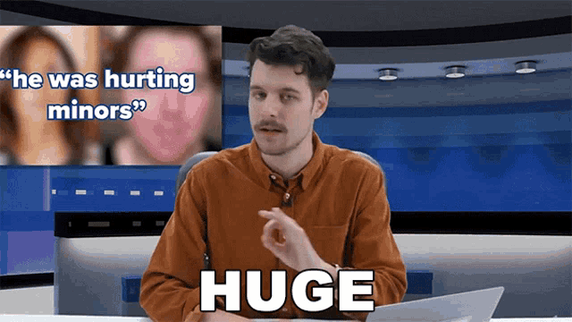 a man sitting at a desk with the word huge in front of him
