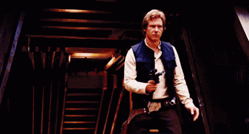 han solo is holding a gun in a dark room with stairs in the background