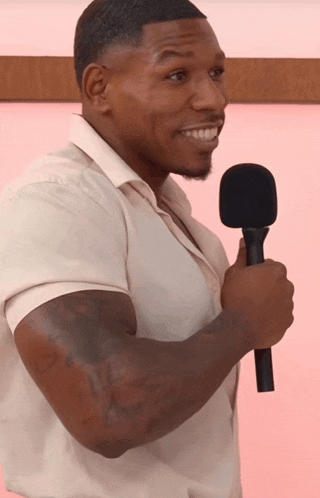 a man in a white shirt holds a black microphone