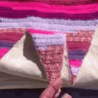 a close up of a person holding a piece of crocheted blanket .