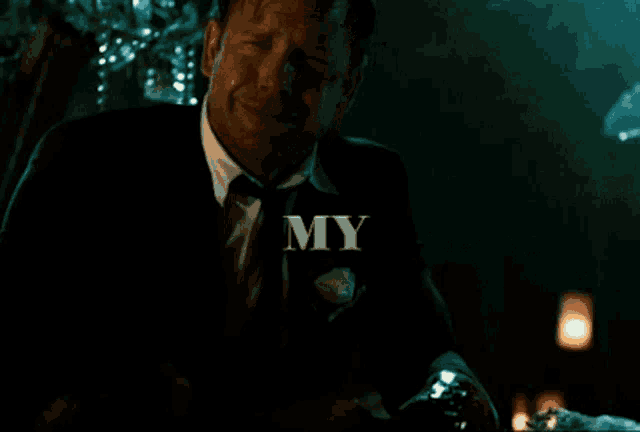 a man in a suit and tie is crying in front of a sign that says " my "