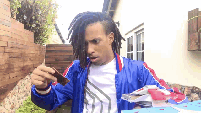 a man with dreadlocks is holding a bar of chocolate in his hand