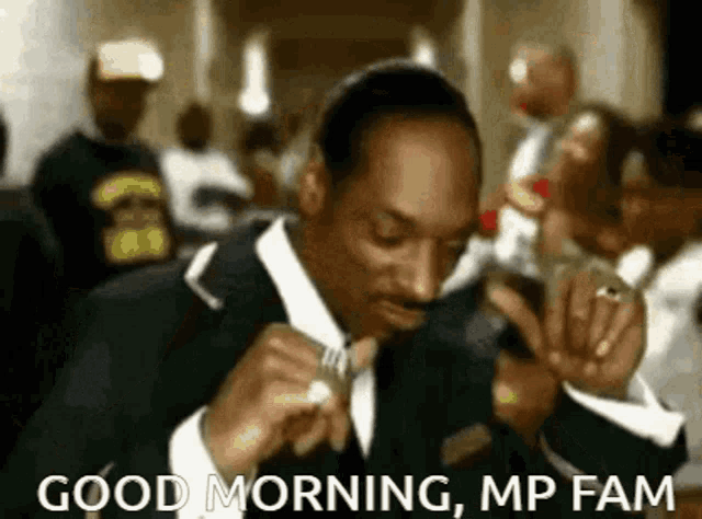 snoop dogg is wearing a suit and tie and smoking a cigarette in a video .