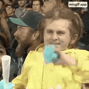 a woman in a yellow jacket is eating blue cotton candy