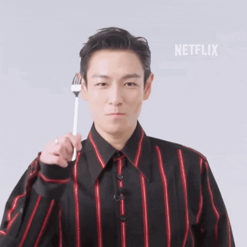 a man in a black and red striped shirt is holding a fork in front of his face