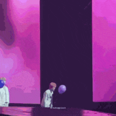 a man is holding a balloon on a stick in front of a pink wall .