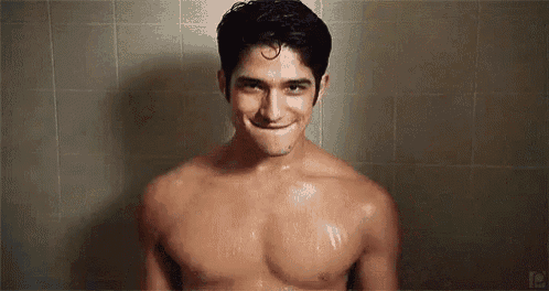 a shirtless man is smiling while taking a shower in a bathroom .