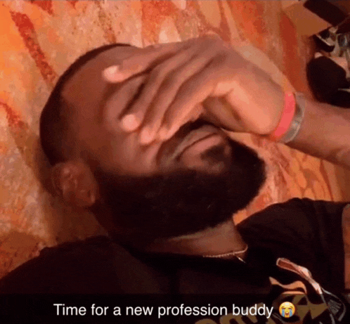 a man with a beard covering his face with his hand with the caption time for a new profession buddy below him