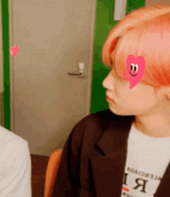 a man with pink hair and a heart on his forehead .