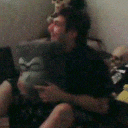 a blurry picture of a man sitting on a couch holding a pillow