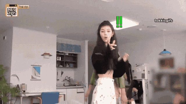 a girl in a crop top is dancing in a room with a sign that says new tips on it