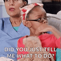 a little girl wearing glasses is sitting next to a woman holding a teddy bear and asking her what to do .