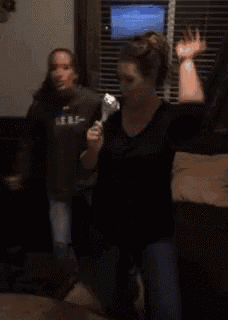 two women are dancing in a living room in front of a window