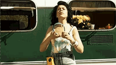 a woman is standing in front of a green trailer holding a purse .