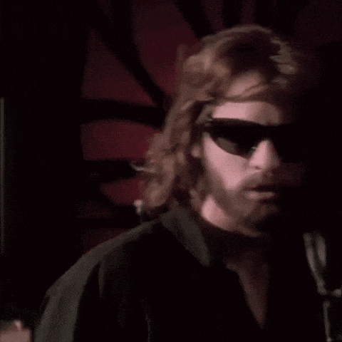 a man with a beard wearing sunglasses looks up into the sky