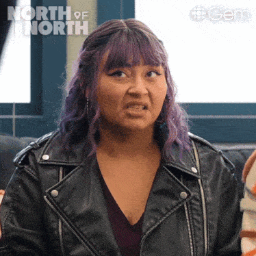 a woman with purple hair and a leather jacket is making a funny face in front of a sign that says north of north