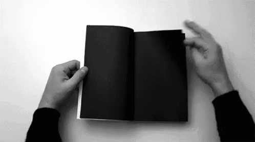 a black and white photo of a person holding a black book open .