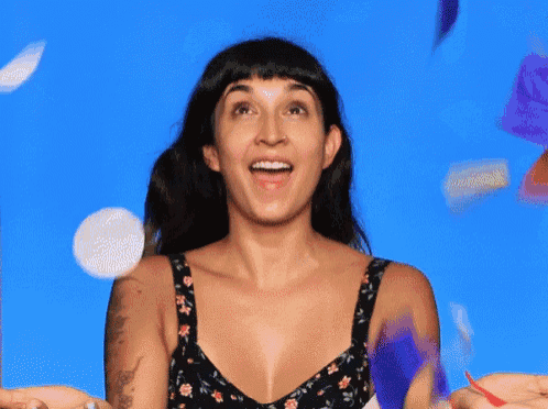 a woman with a tattoo on her arm is standing in front of a blue background with confetti falling around her