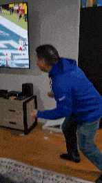 a man in a blue jacket is standing in front of a tv