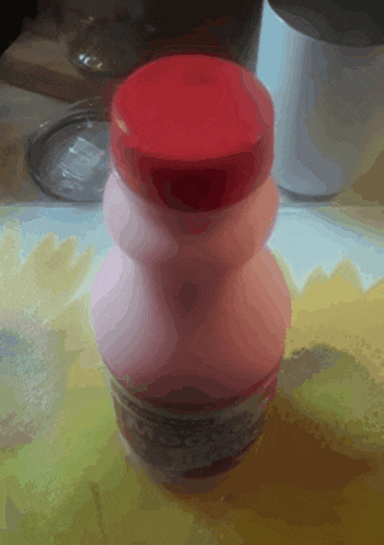 a pink bottle with a red cap is on a table