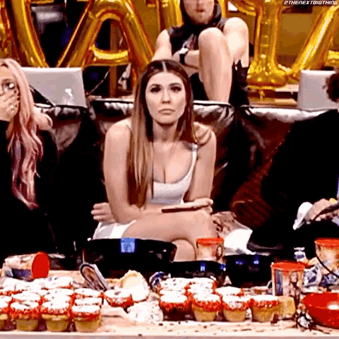 a woman is sitting on a couch in front of a table full of cupcakes
