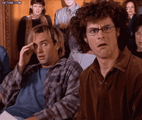 two men are sitting in front of a crowd and one has a surprised look on his face ..
