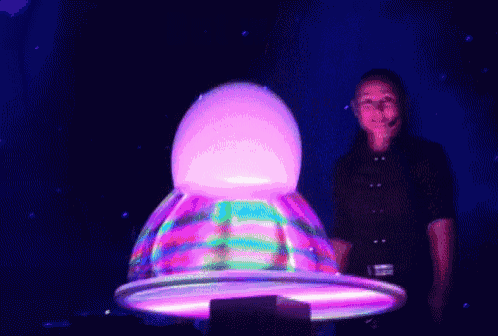 a woman in a black shirt stands in front of a giant bubble