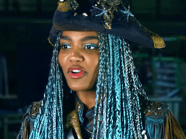 a woman with blue braids wearing a hat