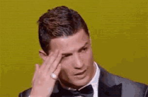 a man in a tuxedo and bow tie wipes his face with his hand