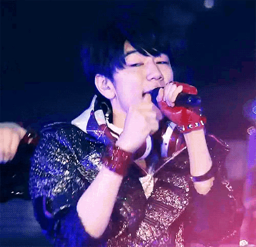 a man singing into a microphone with a red glove on his wrist