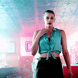 a woman in a blue crop top is standing in front of a sign that says d
