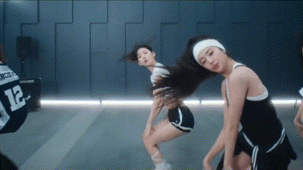 a group of young women are dancing in a dance studio . one of the girls has the number 12 on her jersey .