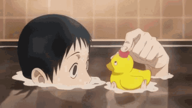 a boy is playing with a yellow rubber duck in a bathtub
