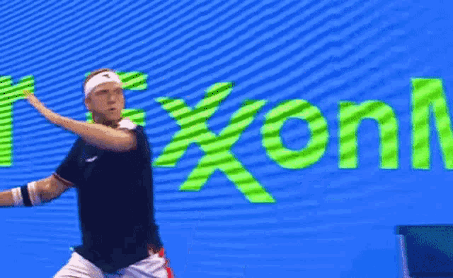 a man is playing tennis in front of a screen that says nexxon