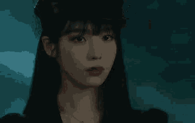 a woman with long black hair and red lipstick is wearing a hat and a necklace .