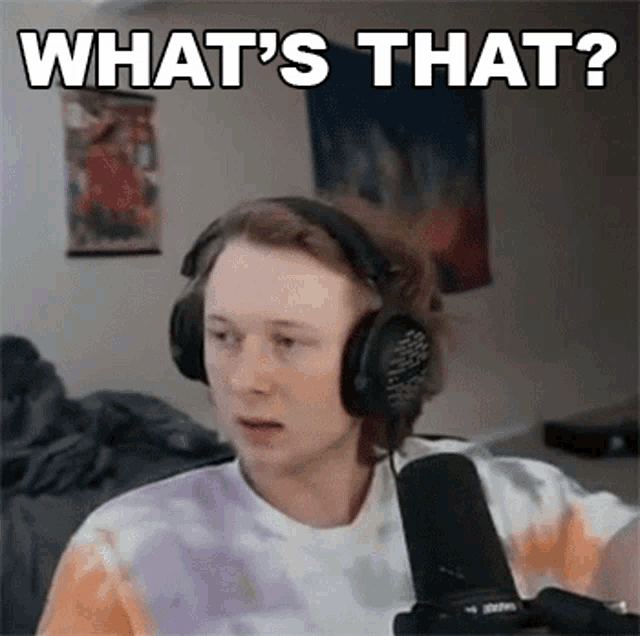 a young man wearing headphones and a tie dye shirt is sitting in front of a microphone and asking what is that .