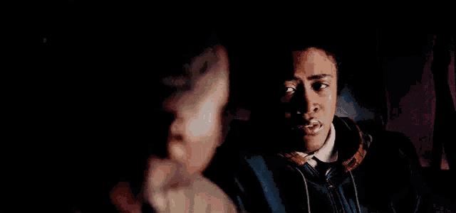 a man and a boy are sitting next to each other in a dark room .