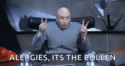 a bald man is sitting at a desk giving the peace sign .