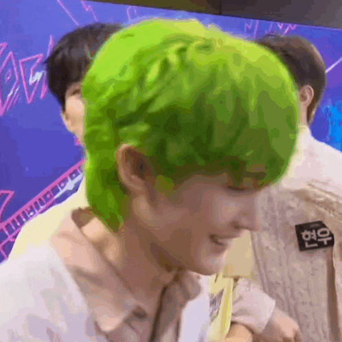a man with green hair is standing next to another man and smiling .
