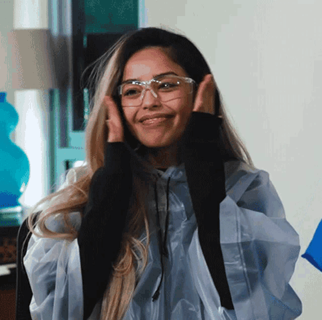 a woman wearing glasses and a plastic poncho smiles