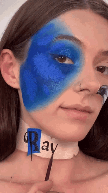 a woman with blue paint on her face has the word ray painted on her neck