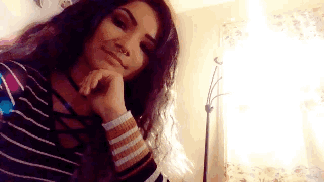 a woman with long hair and a nose ring is smiling for the camera