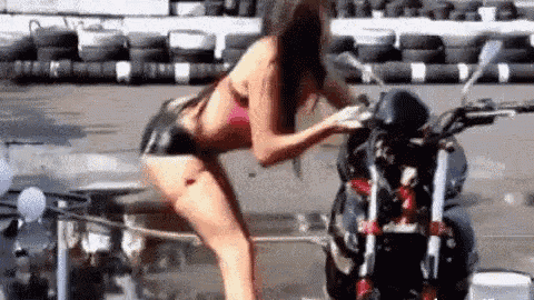 a woman in a bikini is washing a motorcycle on a sunny day .
