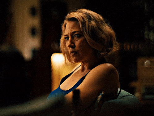 a woman in a blue tank top is holding a wine glass